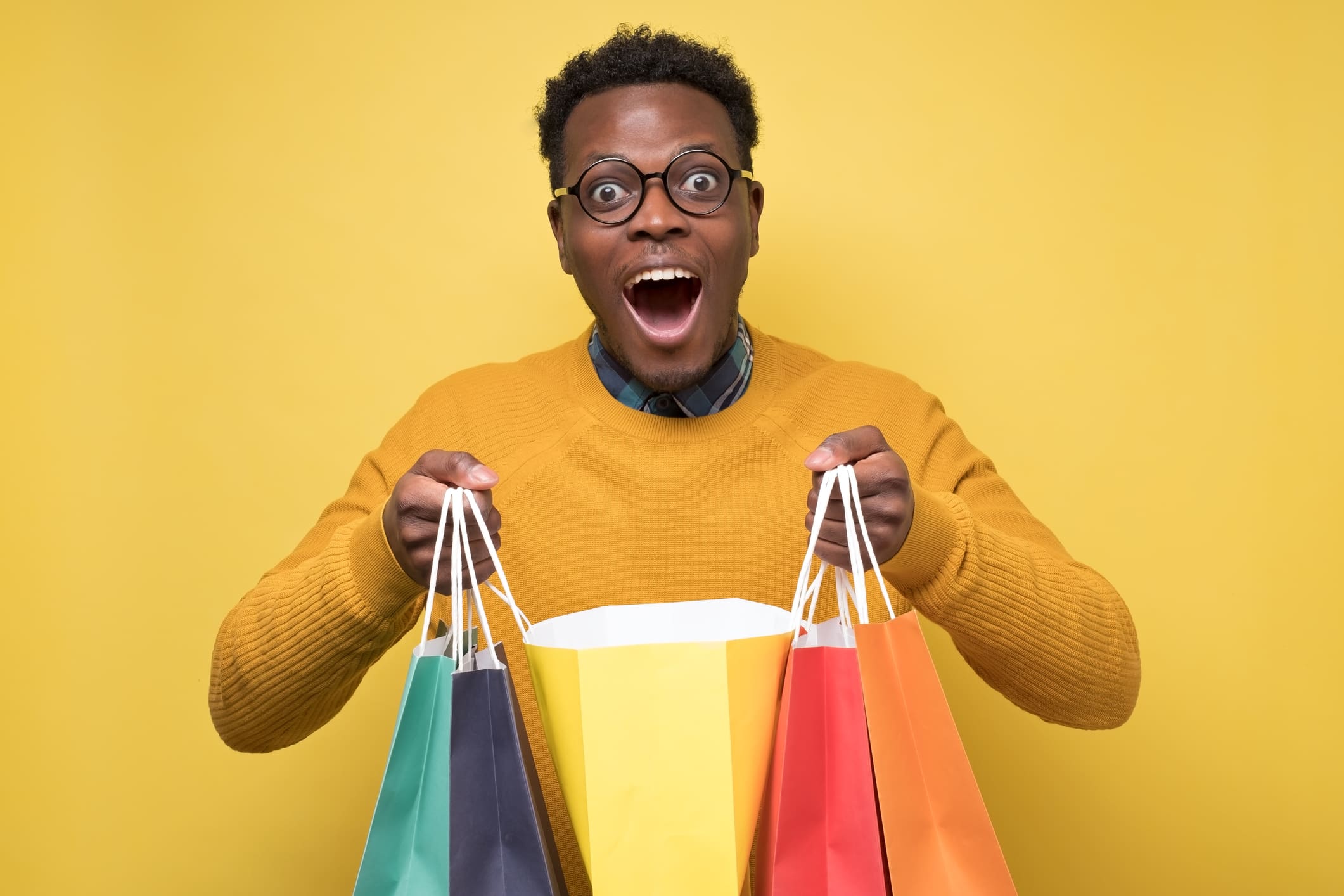Handsome african american young man holds shopping paper bags